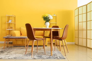 Odadaki yemek masasında güzel kasımpatı çiçekleri olan vazo.