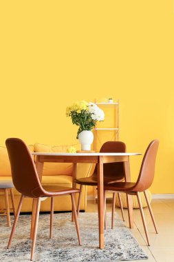 Odadaki yemek masasında güzel kasımpatı çiçekleri olan vazo.