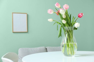 Yemek masasında güzel lale çiçekleri olan bir vazo.