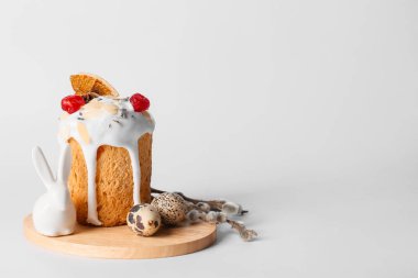 Wooden board with delicious Easter cake, pussy willow branches and eggs on light background