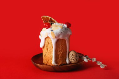 Plate with delicious Easter cake, egg and pussy willow branches on red background