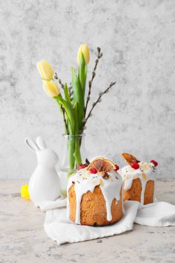 Delicious Easter cakes and pussy willow branches with tulip flowers on light background