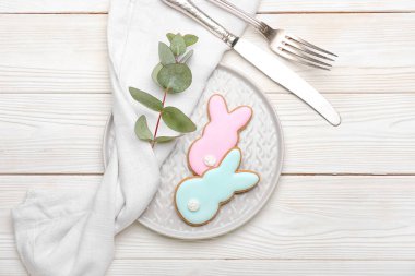 Lezzetli Paskalya kurabiyelerinin olduğu tabak beyaz ahşap arka plandaki tavşanda.