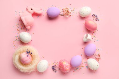 Pembe arka planda boyanmış Paskalya yumurtaları, tavşanlar ve çiçeklerden yapılmış çerçeve