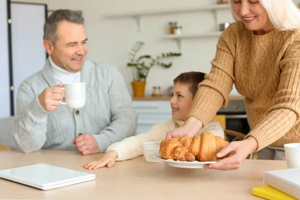 Senior Woman Putting Plate Croissants Table Her Husband Little Grandson — Stock Photo, Image
