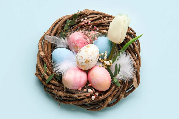 Mavi Arka Planda Boyanmış Paskalya Yumurtaları Çiçekli Yuva — Stok fotoğraf