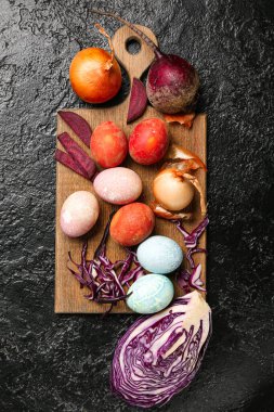 Tahta tahta tahta tahta, güzel Paskalya yumurtaları ve koyu arkaplanda doğal boyalar.
