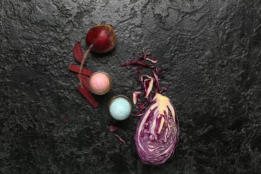 Güzel Paskalya yumurtaları, mor lahana ve siyah arka planda pancar taşıyan tutucular.