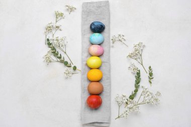 Güzel Paskalya yumurtaları, çigila çiçekleri ve açık arkaplanda okaliptüs dalları olan kompozisyon