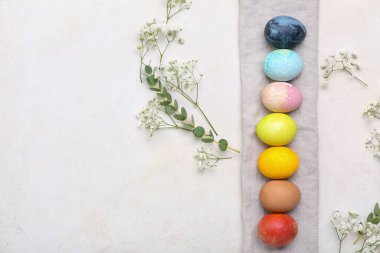 Güzel Paskalya yumurtaları, çigila çiçekleri ve açık arkaplanda okaliptüs dalları olan kompozisyon