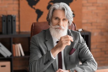 Ofiste çalışan olgun sakallı bir iş adamı.