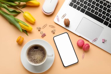 Kahve, dizüstü bilgisayar, cep telefonu ve çiçeklerle renklendirilmiş kompozisyon