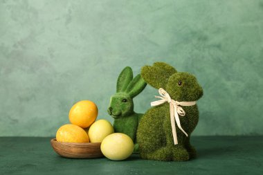 Güzel Paskalya tavşanları ve yeşil arka planda boyanmış yumurtalar.