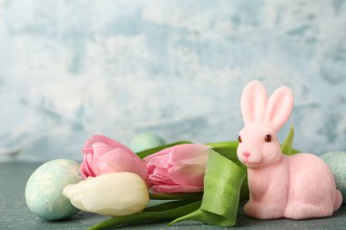 Güzel Paskalya tavşanı, mavi arka planda boyanmış yumurta ve lale çiçekleri.