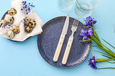 Paskalya kutlaması için güzel bir masa ve mavi arka planda çiçekler.