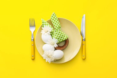 Paskalya kutlaması için güzel bir masa ve sarı arka planda çiçekler.