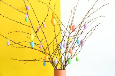 Ağaç dalları ve Paskalya yumurtaları olan vazolar odada renk duvarının yanında, yakın plan.