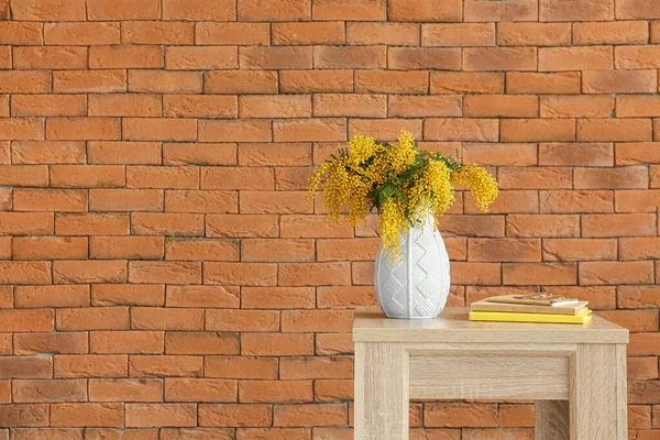 レンガの壁の近くのテーブルの上にミモザの花 眼鏡の花瓶 — ストック写真