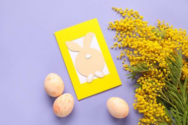 Güzel Paskalya kompozisyonu, tebrik kartı, mor arka planda boyanmış yumurta ve çiçekler.