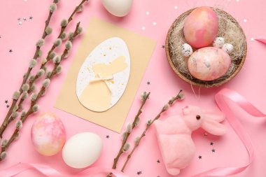 Beautiful Easter composition with greeting card, painted eggs and pussy willow branches on pink background