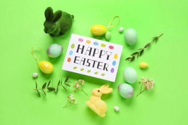Yeşil arka planda güzel Paskalya kompozisyonu, yumurta, tavşan ve çiçek resimleri.