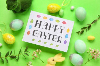 Yeşil arka planda güzel Paskalya kompozisyonu, yumurta, tavşan ve çiçek resimleri.