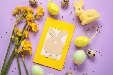Güzel Paskalya kompozisyonu, tebrik kartı, boyalı yumurta, tavşan ve mor arka planda çiçekler.