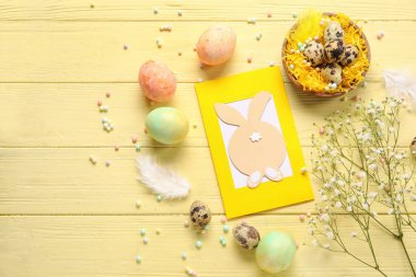 Güzel Paskalya kompozisyonu tebrik kartı, renkli ahşap arka planda boyanmış yumurta ve çiçekler.