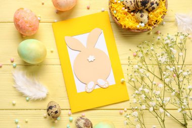 Güzel Paskalya kompozisyonu tebrik kartı, renkli ahşap arka planda boyanmış yumurta ve çiçekler.