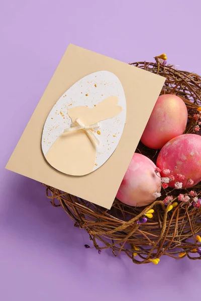 Φωλιά Βαμμένα Πασχαλινά Αυγά Και Ευχετήρια Κάρτα Μωβ Φόντο Closeup — Φωτογραφία Αρχείου