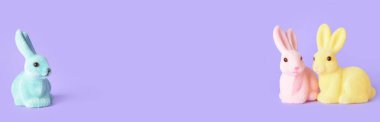 Renkli arkaplan üzerinde paskalya tavşanlarının şirin heykelcikleri ve metin için boşluk