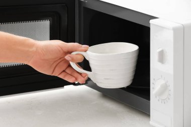 Mikrodalga fırından fincanı alan genç kadın, yakın plan.