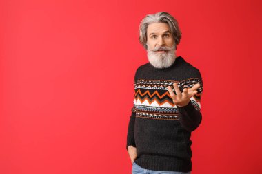 Kırmızı arka planda örgü süveter giyen son sınıf öğrencisi.