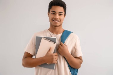 Arka planda not defterleri ve sırt çantası olan Afrikalı Amerikalı bir erkek öğrenci.