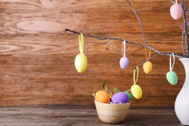 Ahşap arka planda ağaç dalları olan farklı paskalya yumurtaları ve vazoları.