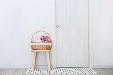 Paskalya desenli sepet. Duvarın yanındaki tahta taburede.