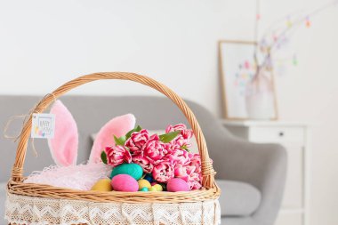 Paskalya yumurtaları, tavşan kulakları ve lalelerle dolu sepet.