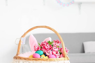 Paskalya yumurtaları, tavşan kulakları ve lalelerle dolu sepet.