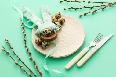 Beautiful table setting for Easter celebration and pussy willow branches on color background, closeup