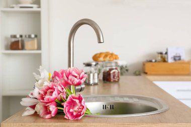 Mutfağın içinde bir buket güzel çiçekle birlikte lavabo.