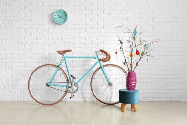 Paskalya dekorlu ağaç dalları ve beyaz tuğla duvarın yanında bisiklet