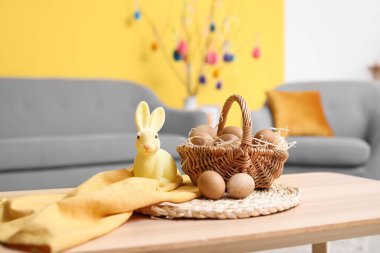 Paskalya tavşanı ve sepet, oturma odasındaki ahşap masada yumurtalar.