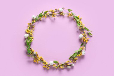 Paskalya yumurtalı güzel bir çelenk ve mor arka planda çiçekler.