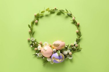 Yeşil arka planda Paskalya yumurtası ve çiçekli güzel bir çelenk.