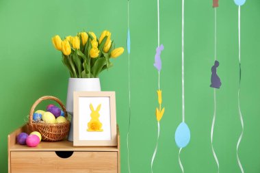 Lale buketi, fotoğraf çerçevesi ve sepeti. Paskalya yumurtaları renkli duvarın yanında.