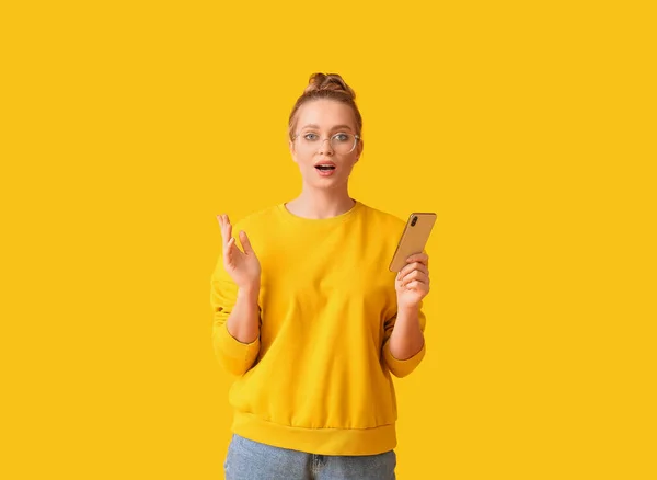 Zaskoczona Młoda Kobieta Telefonem Komórkowym Żółtym Tle — Zdjęcie stockowe