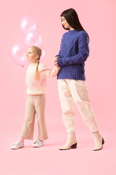 분홍색 배경에 풍선을 소녀와 스웨터를 어머니 — 스톡 사진