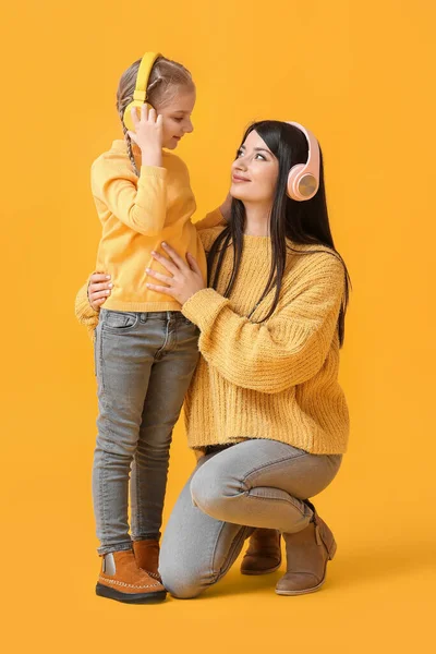 Malá Dívka Její Matka Sluchátkách Teplé Svetry Žlutém Pozadí — Stock fotografie