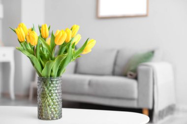 Oturma odasındaki masanın üstünde güzel laleler olan vazo.