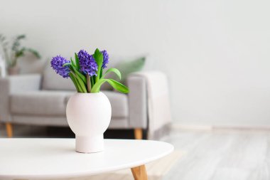 Aydınlık oturma odasındaki masada çiçek açan vazo.